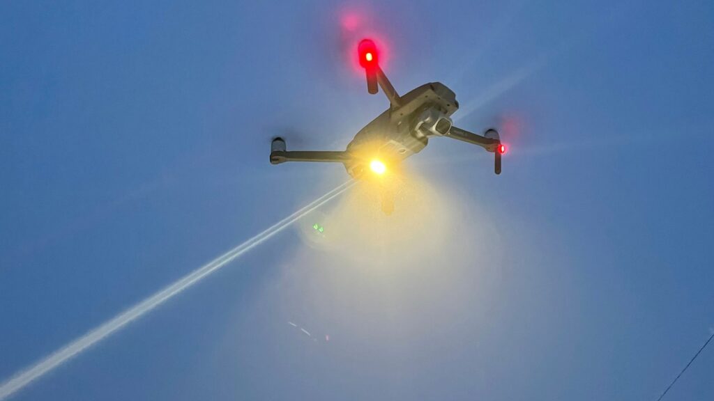 Drone con le luci accese in volo al crepuscolo