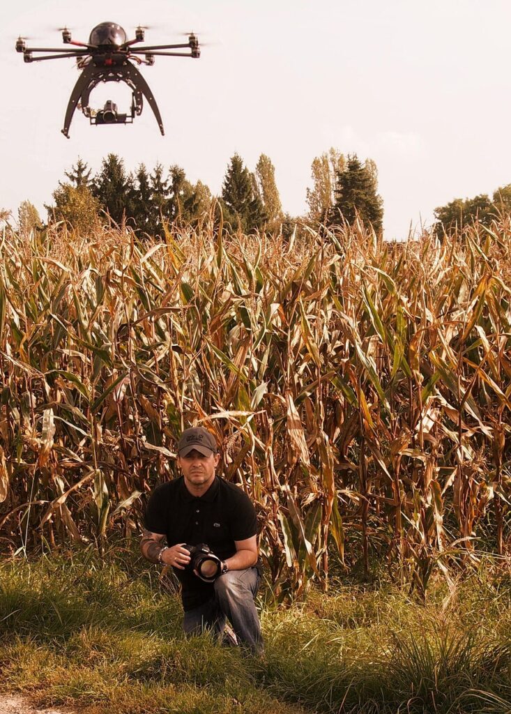 Pilota con radiocomando e drone esacottero sopra un campo