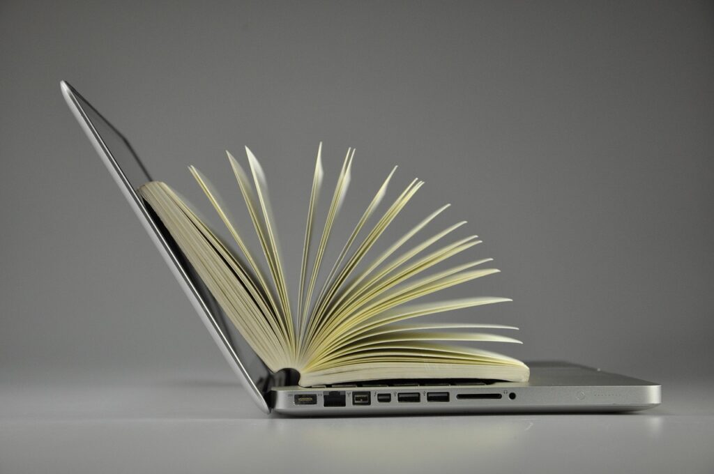 Computer portatile aperto con un libro tra le pagine